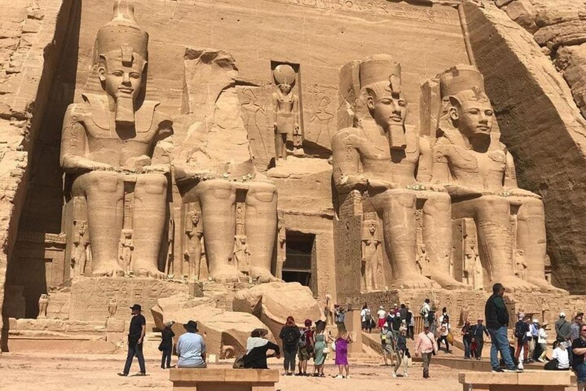 Un grupo de personas de pie frente a una gran estatua