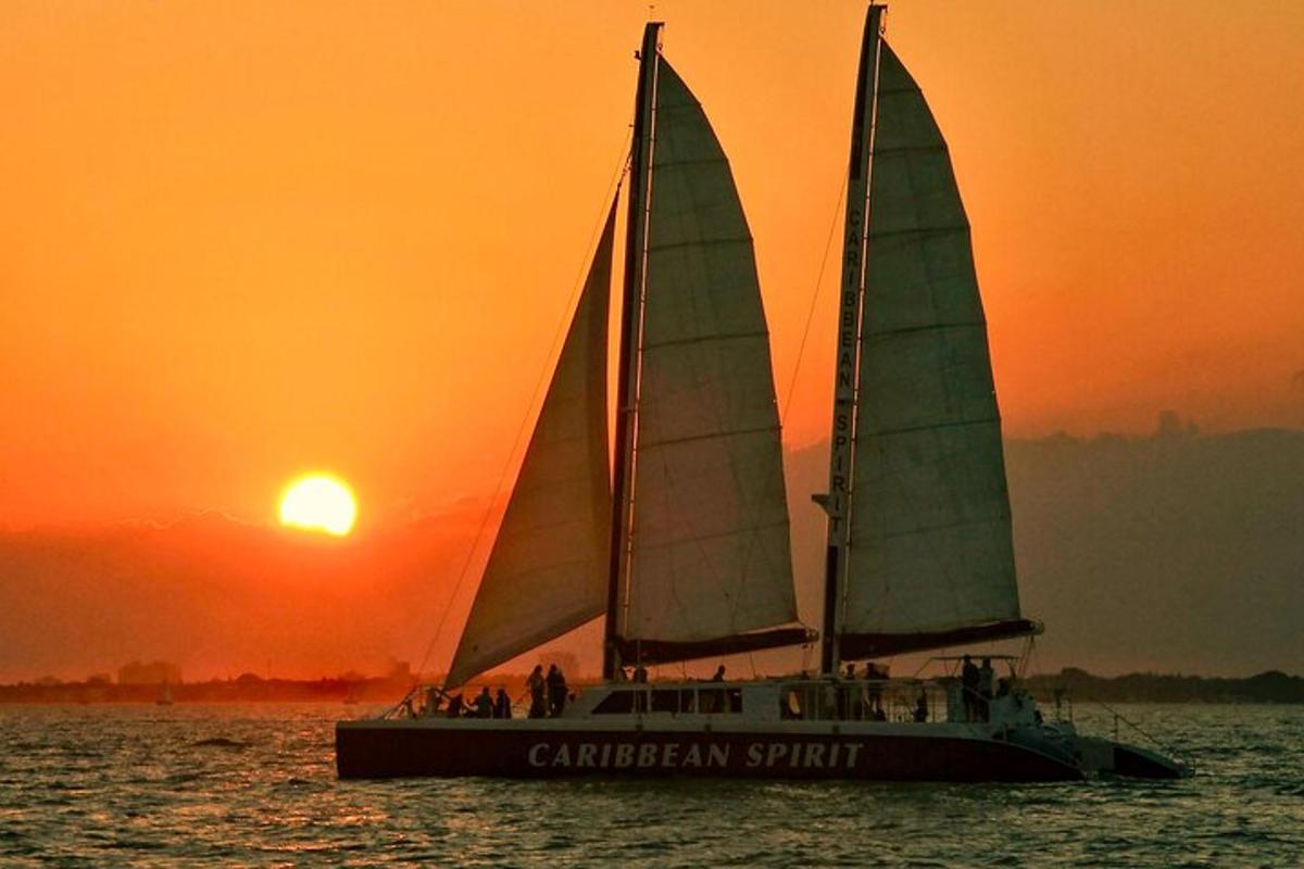 two sailboats in the water with the sunset in the background
