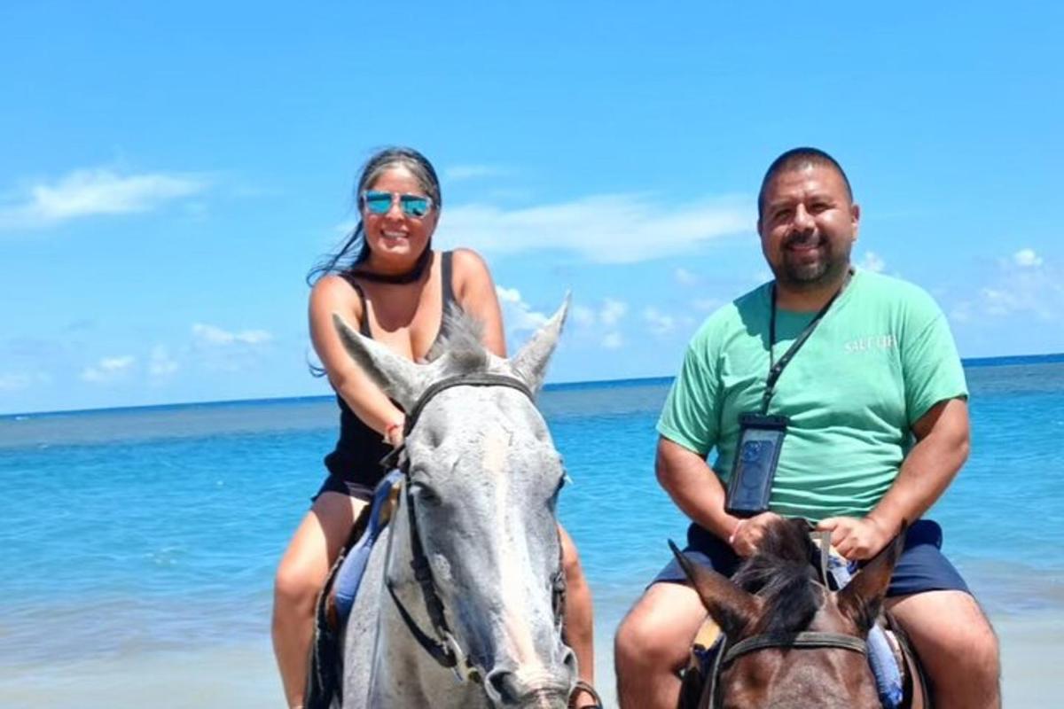 seorang lelaki dan seorang wanita menunggang kuda di pantai