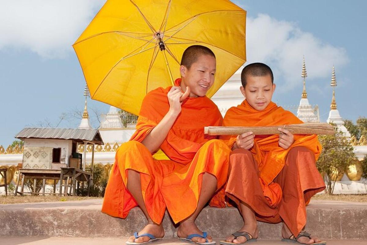two monks sitting on a ledge with an umbrella