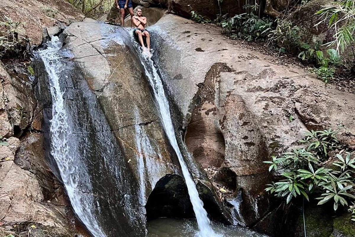 a woman sitting on a rock next to a waterfall