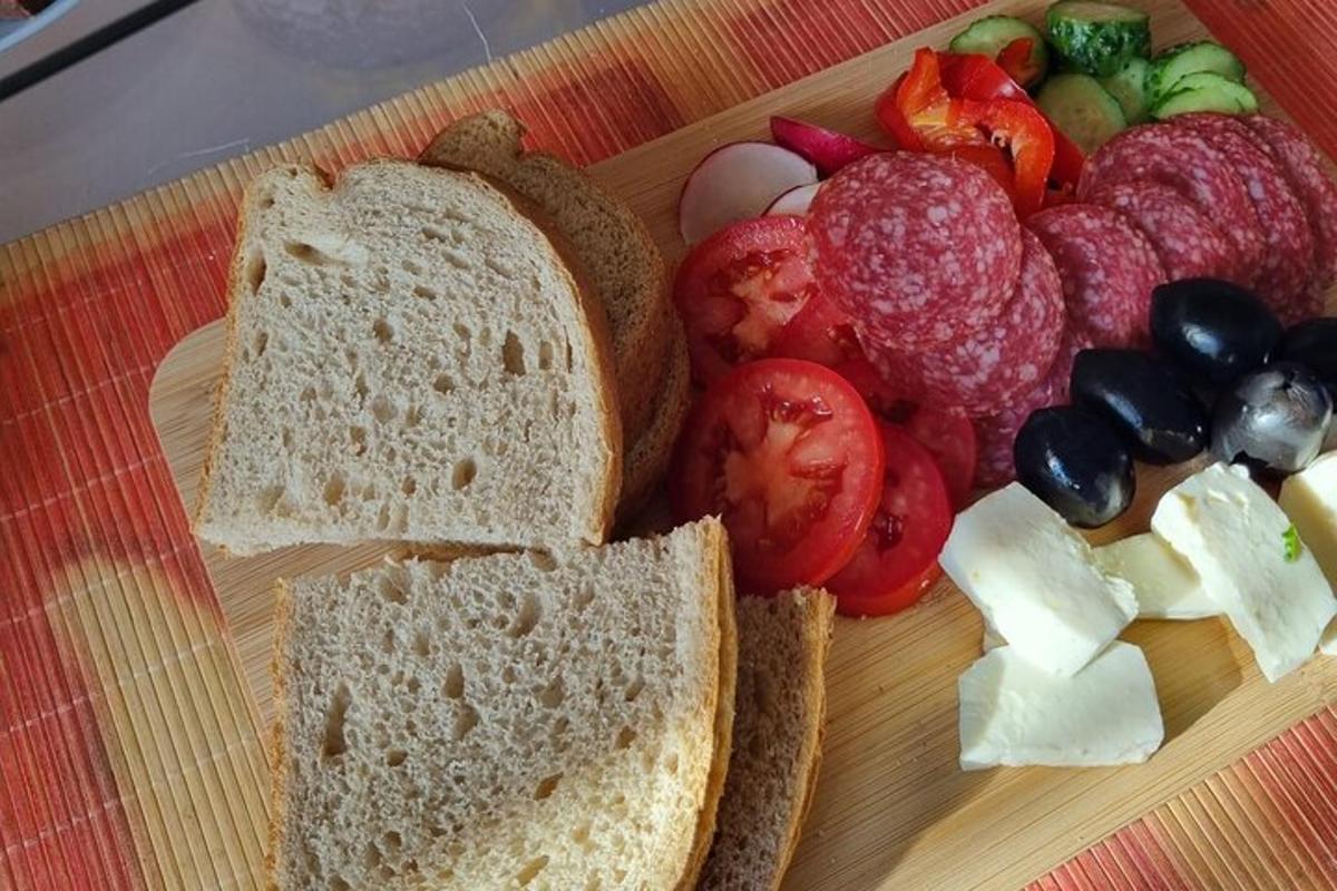 a cutting board with a sandwich and a plate of fruit