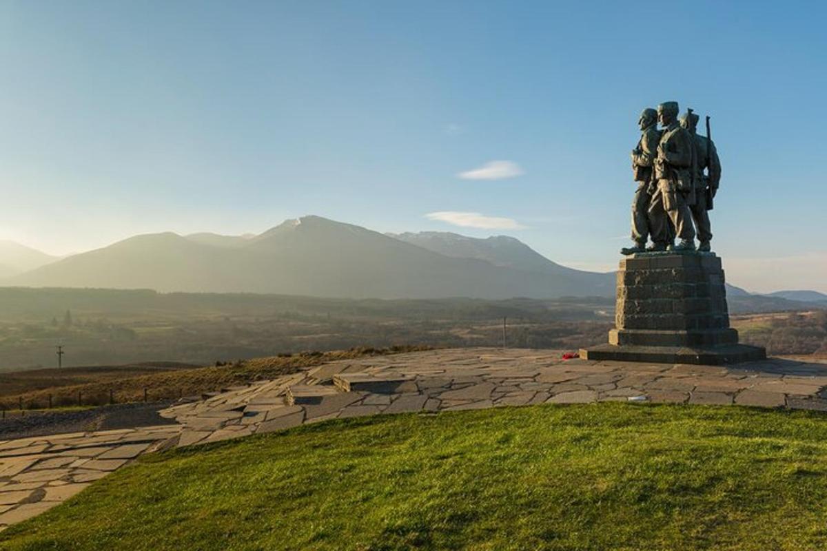 una statua in cima a una collina con le montagne sullo sfondo