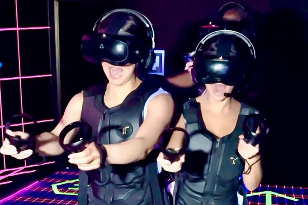 Dos mujeres que llevan equipos de realidad virtual en una habitación.