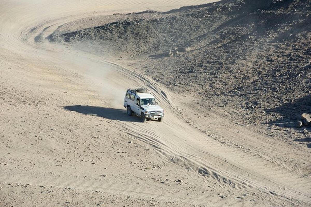 a truck driving down a dirt road in the desert
