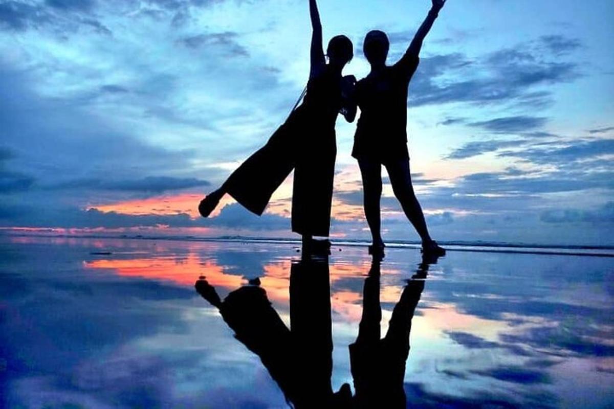 una pareja saltando en la playa al atardecer