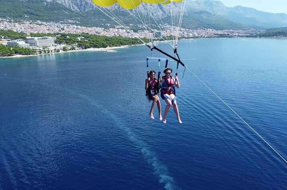 two people are hanging from a parachute over the water