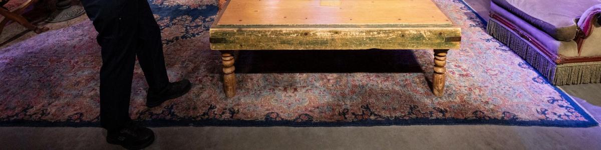 a person standing next to a wooden table on a rug