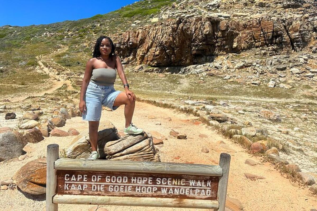 uma mulher em pé no topo de uma placa em uma montanha
