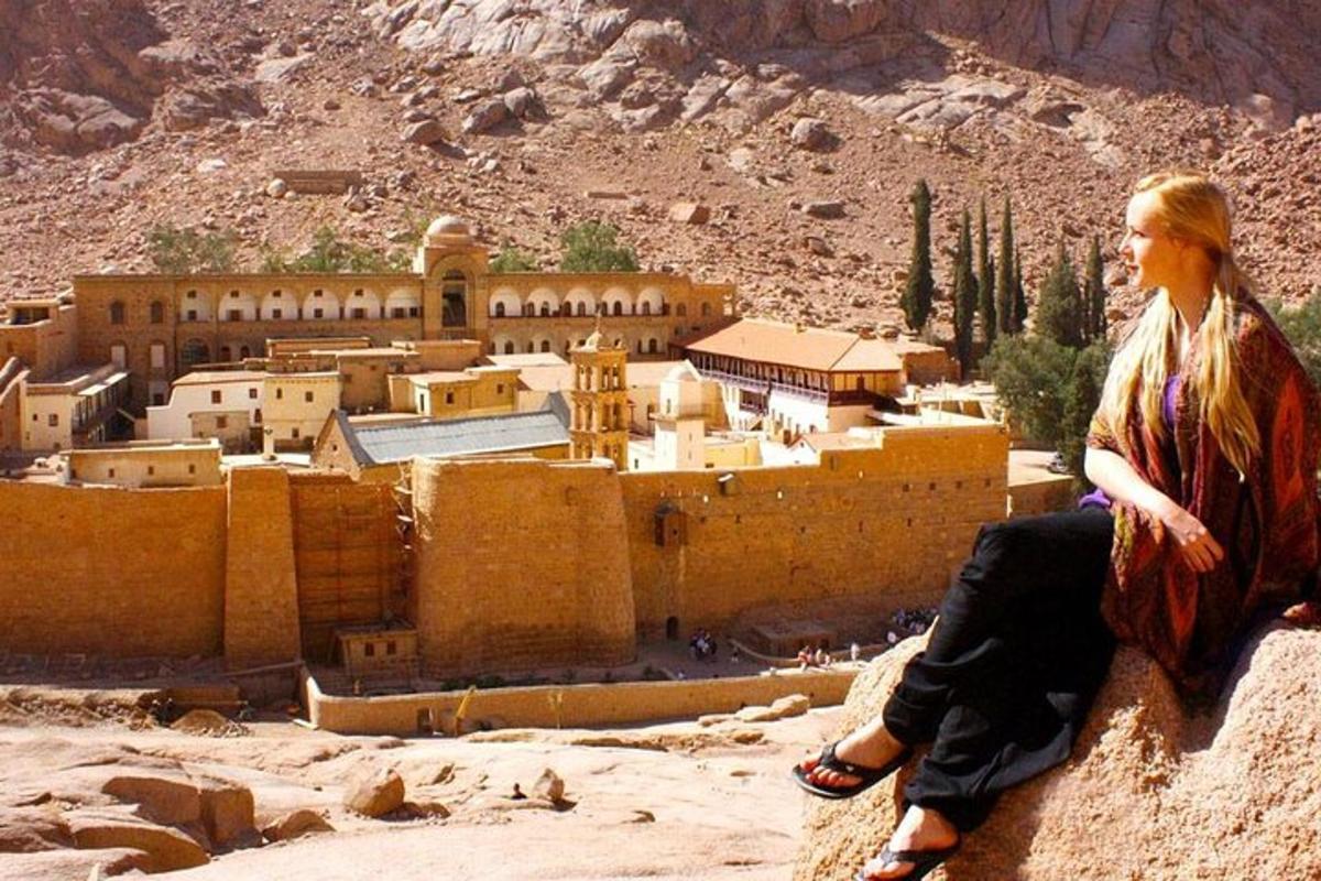 a woman sitting on a rock looking at a city