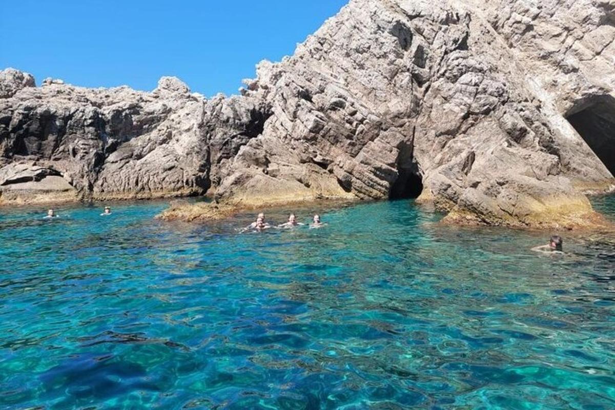 a group of people swimming in the water near a cave