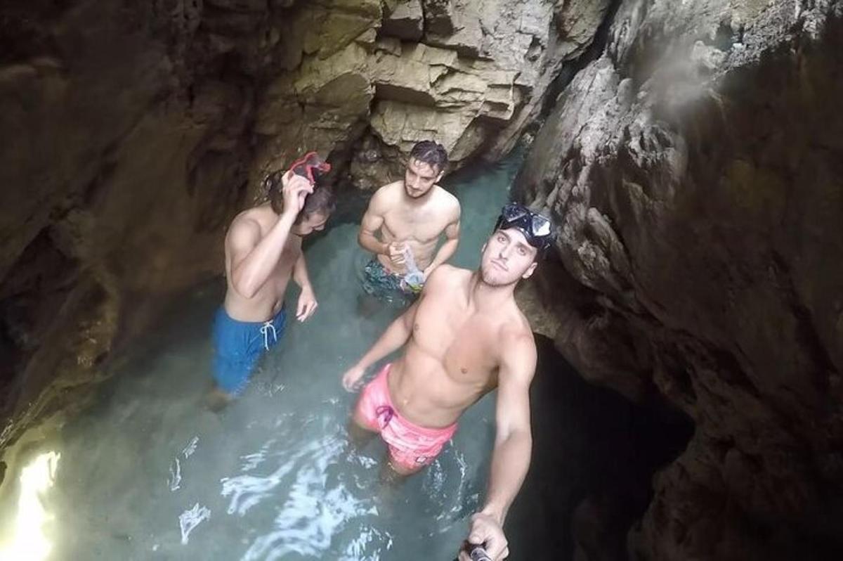 three men in a pool of water in a cave