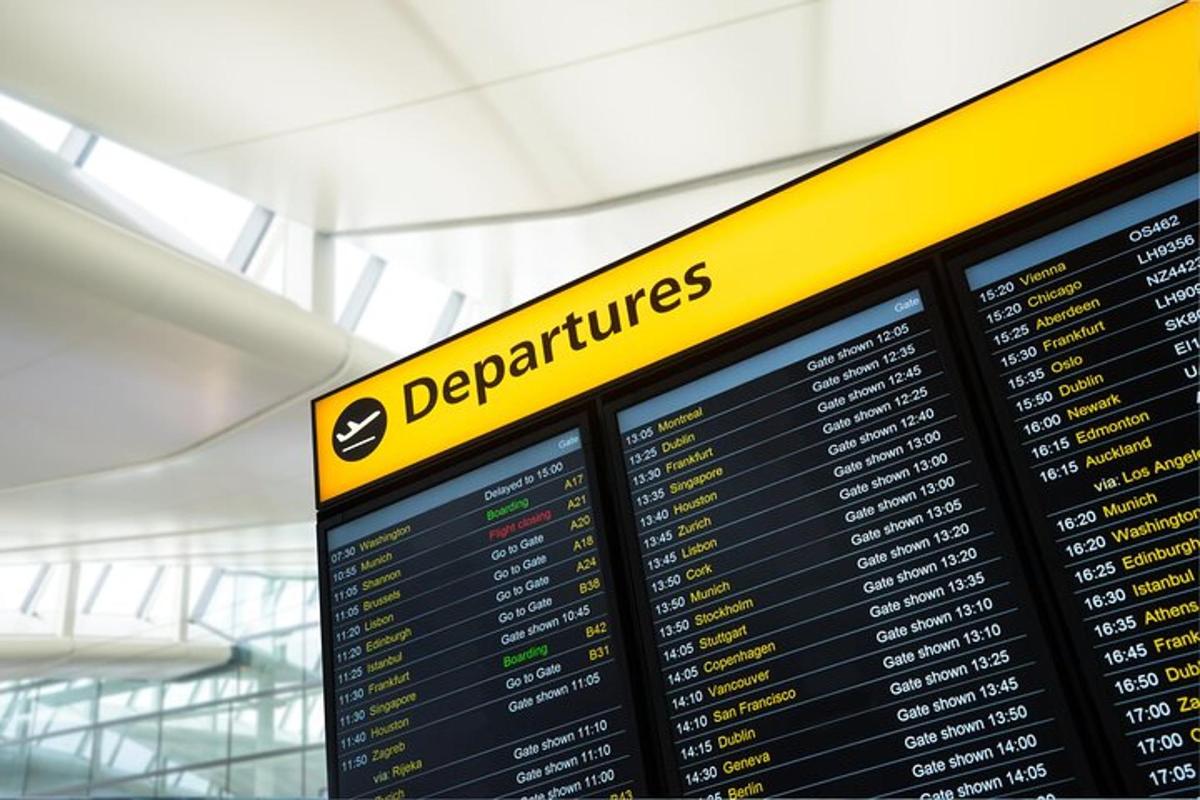 um painel de embarque em um aeroporto com uma placa amarela