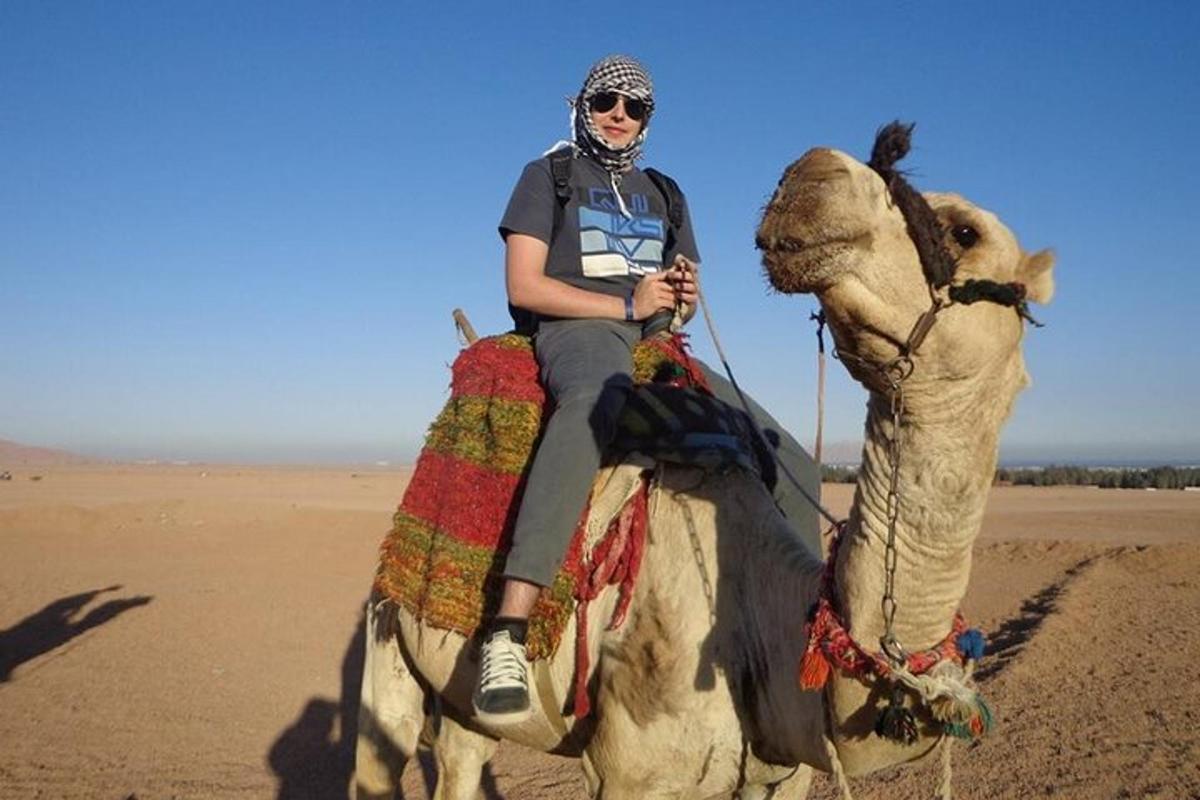 een vrouw die op een kameel rijdt in de woestijn