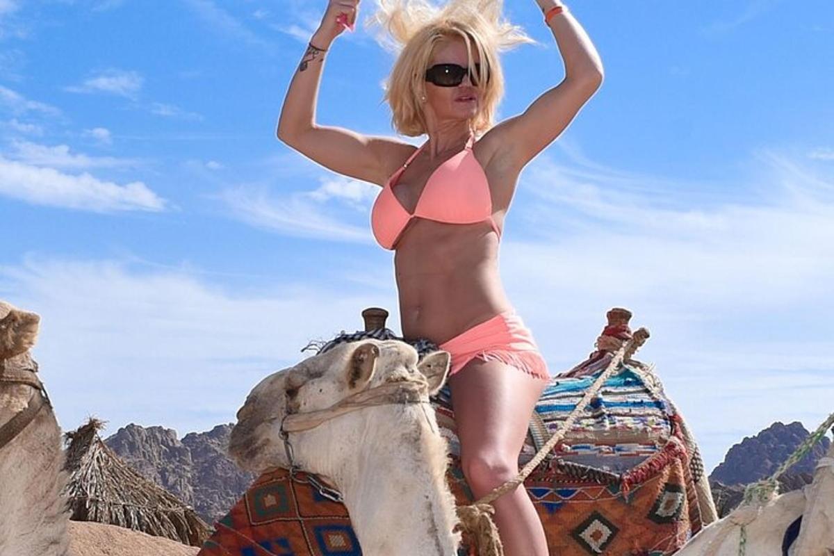 uma mulher de biquíni sentada em cima de um camelo