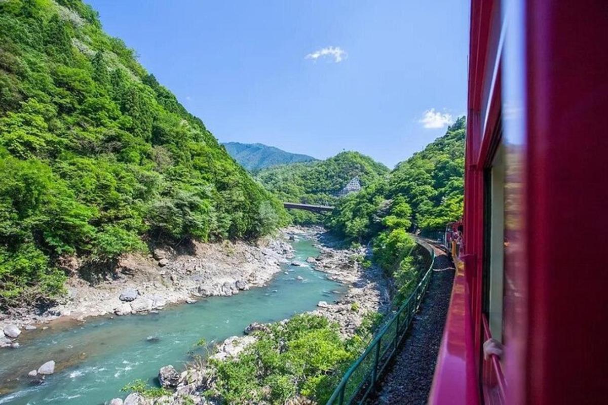 un tren vermell que baixa per un riu a prop d'una muntanya