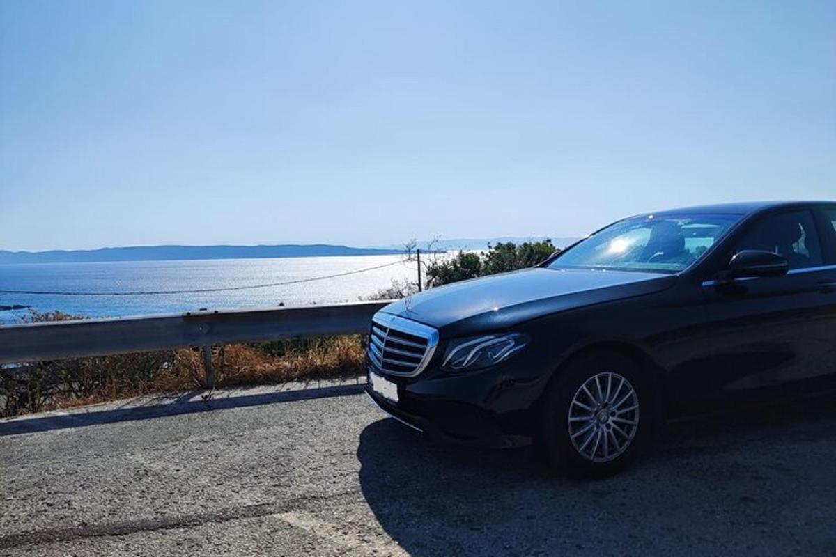 a black car parked on a road near the ocean
