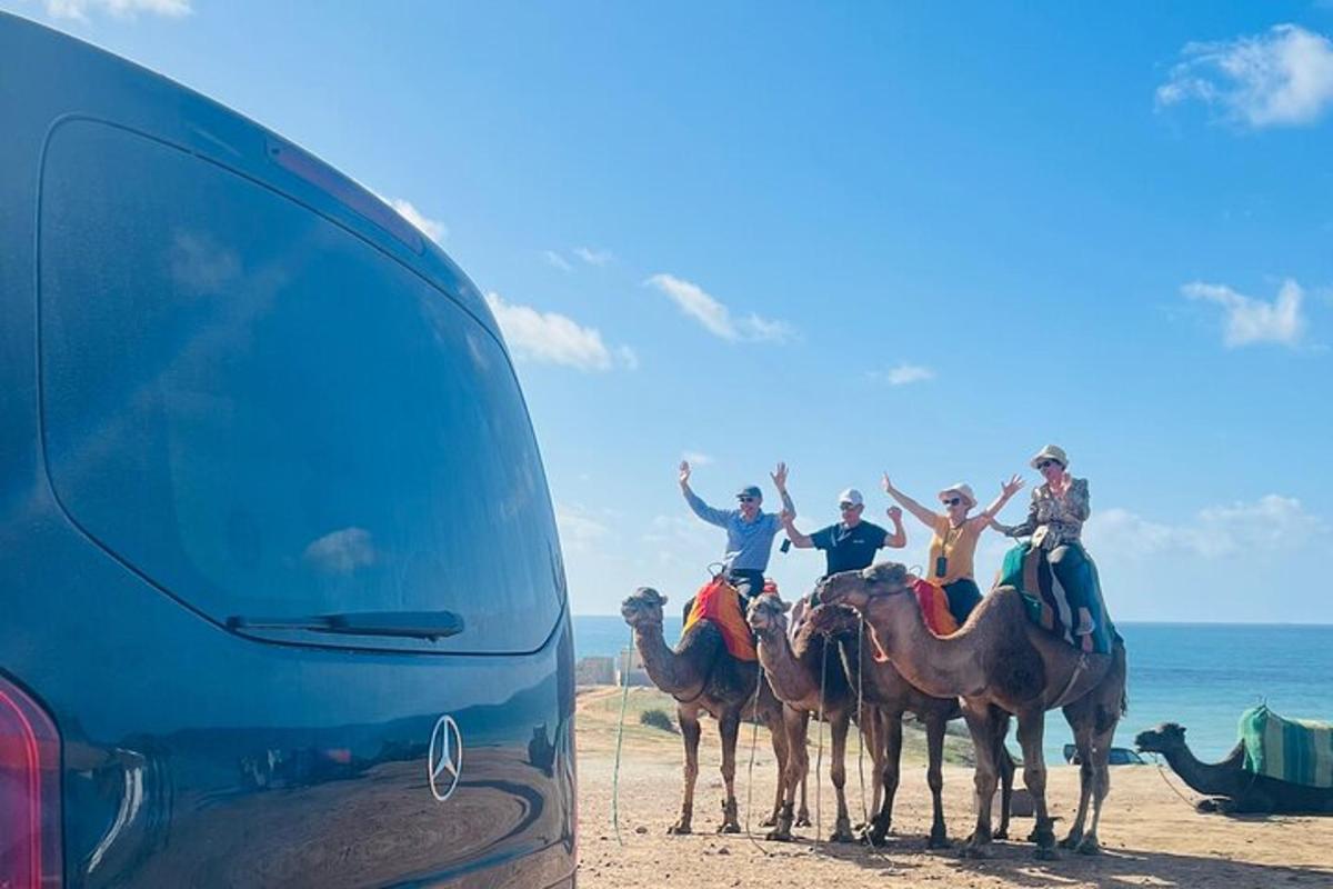 un gruppo di persone a cavallo di cammelli sulla spiaggia