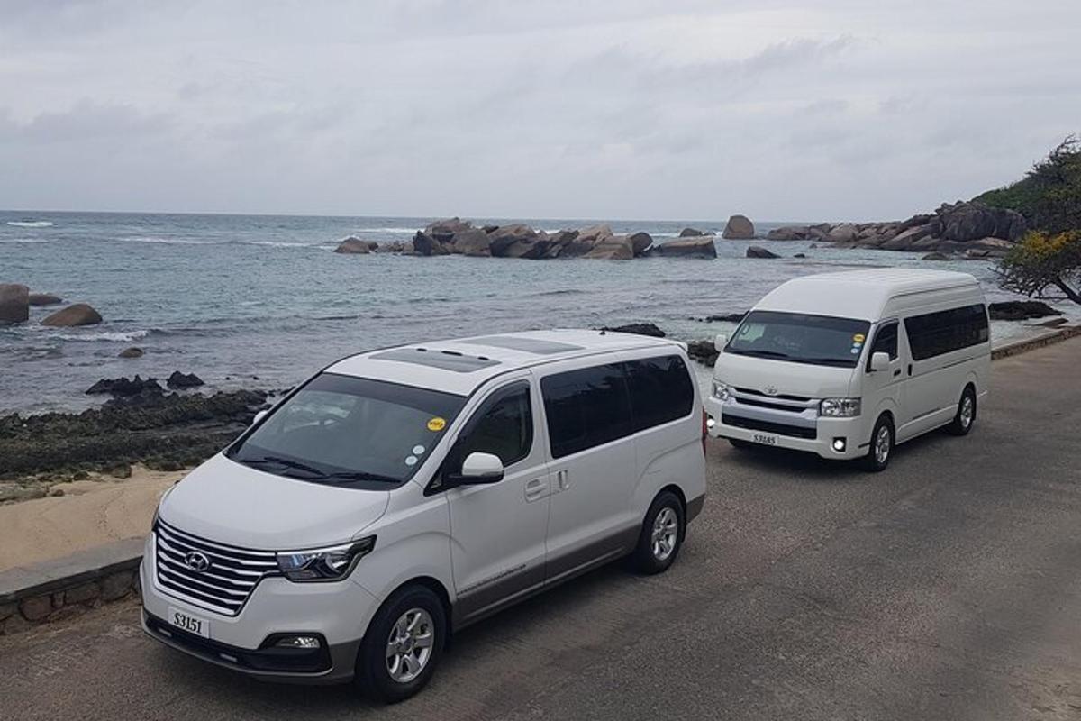 两辆白色货车停在海边的路上