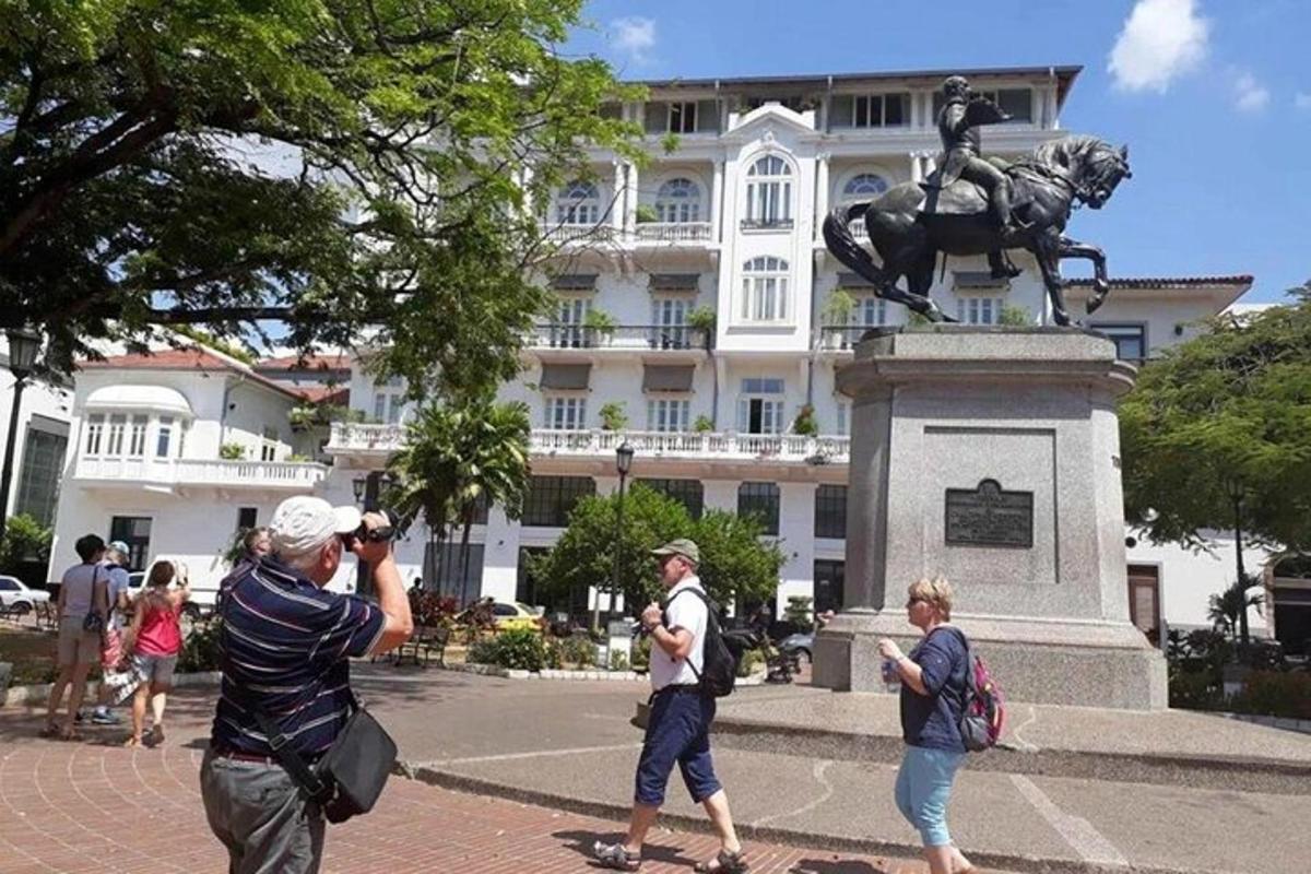 muž fotografující sochu před budovou
