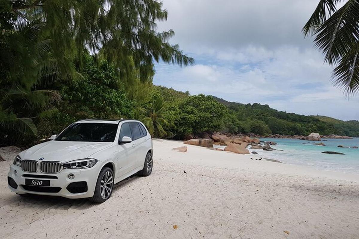 ein weißes Auto, das an einem Strand in der Nähe des Ozeans geparkt ist