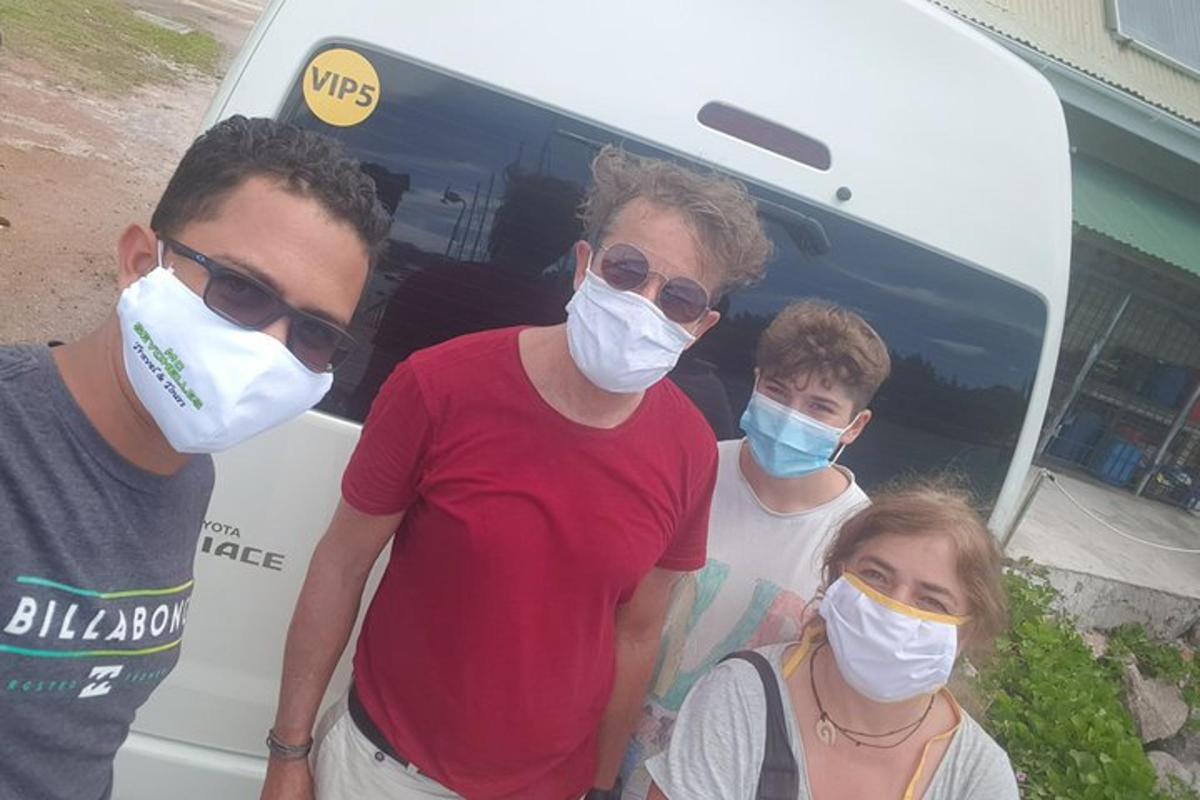 four people wearing masks standing in front of a bus