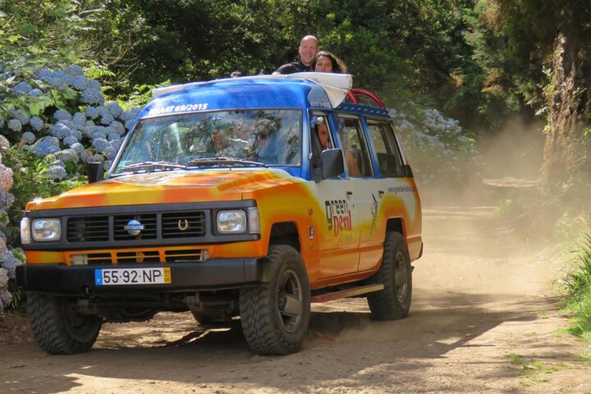 oranžový a modrý nákladní vůz jedoucí po nezpevněné cestě