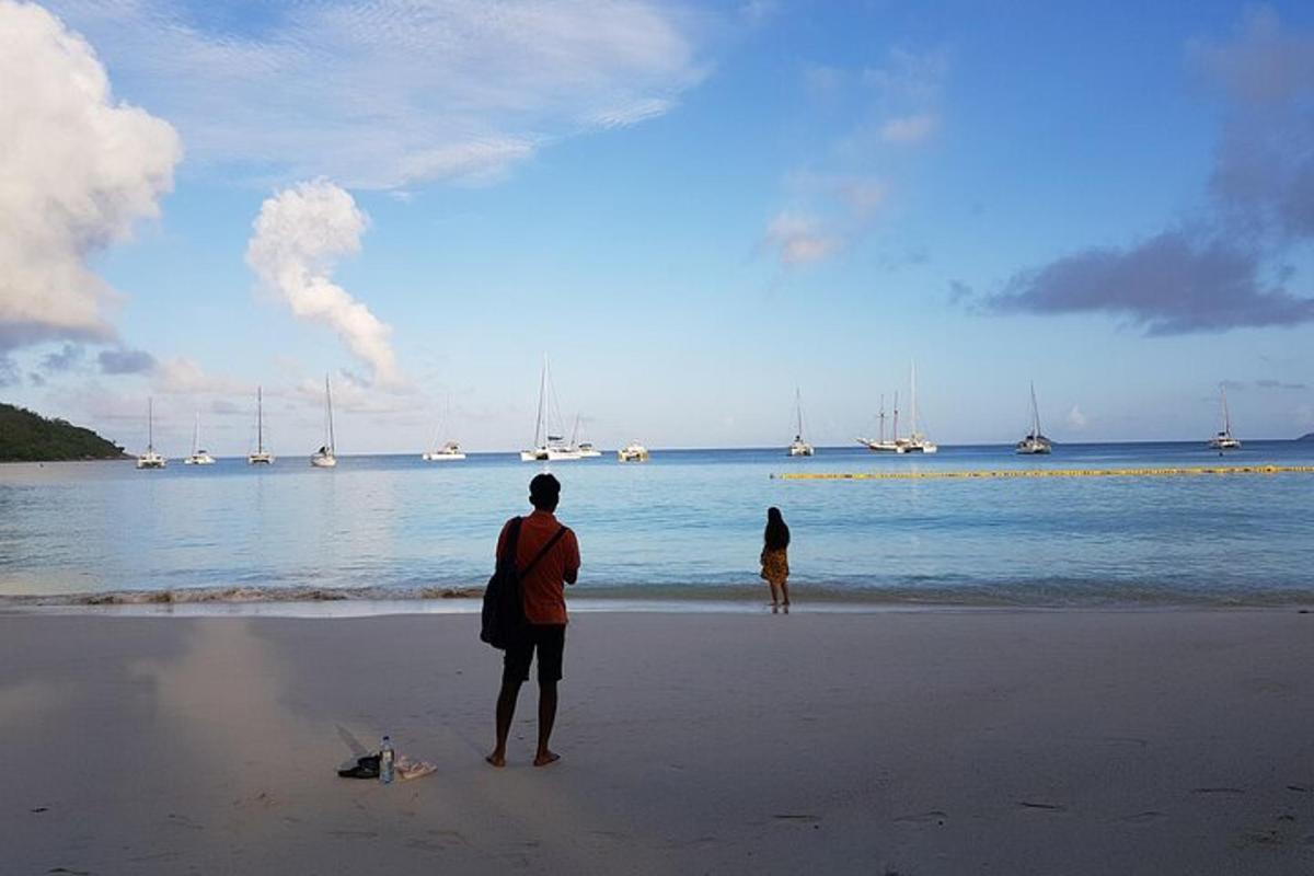 zwei leute stehen am strand und schauen aufs wasser
