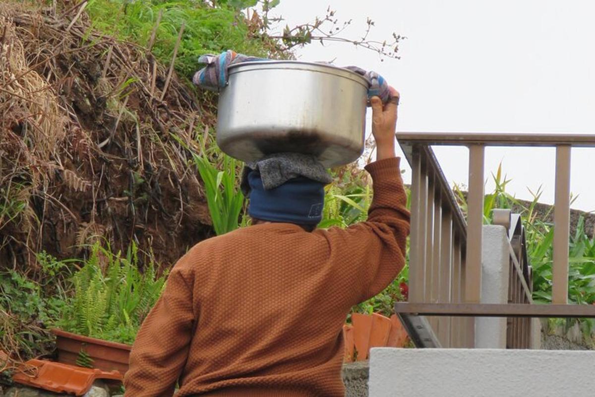 uma pessoa carregando uma panela na cabeça