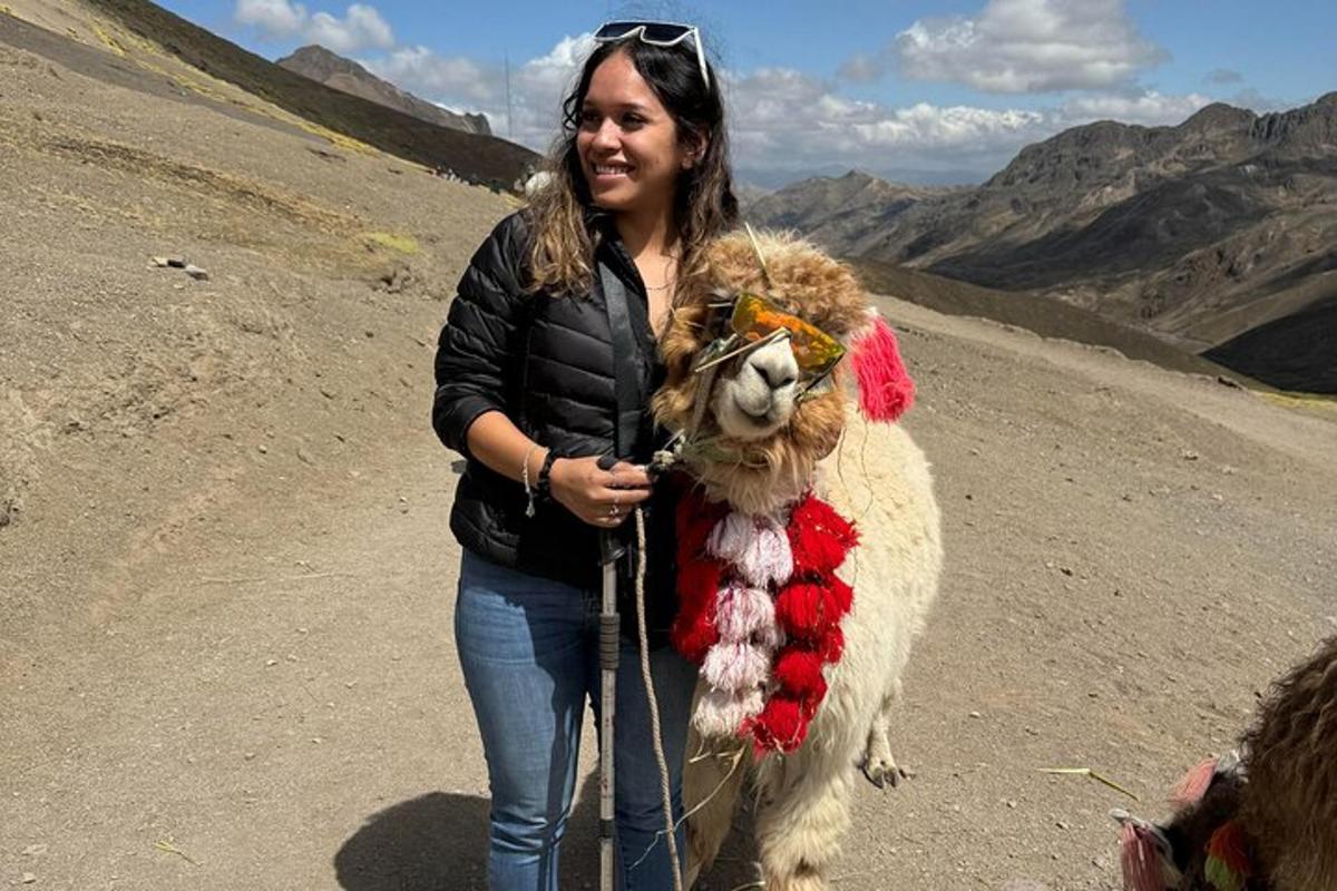 Una mujer sostiene una llama en una montaña.