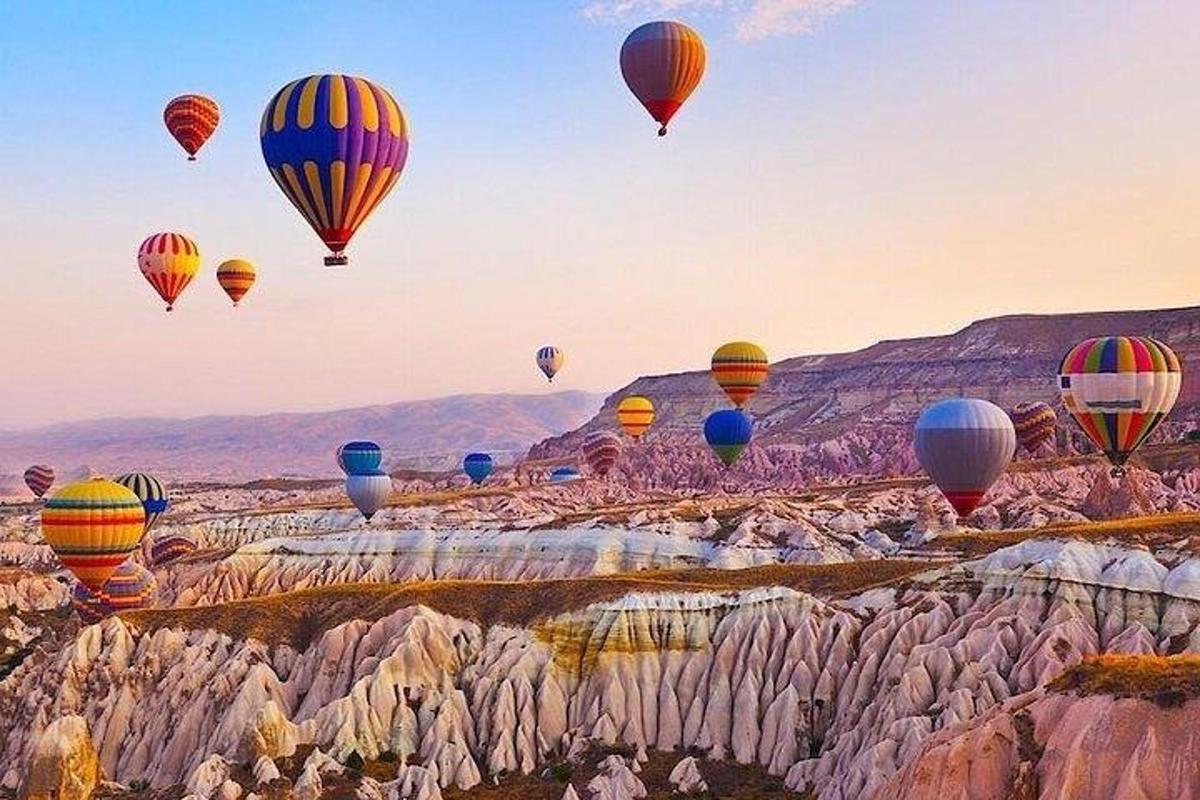 a bunch of hot air balloons flying over rocks