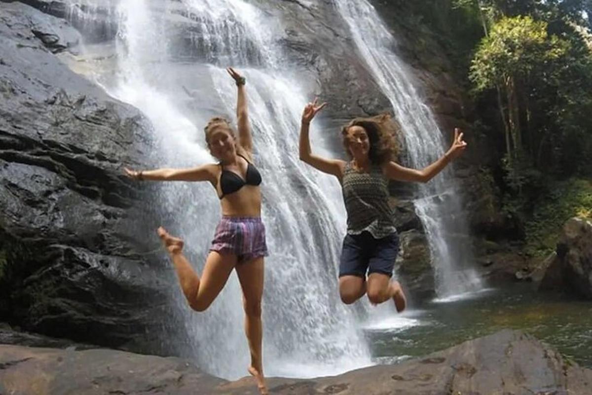 two girls jumping in front of a waterfall