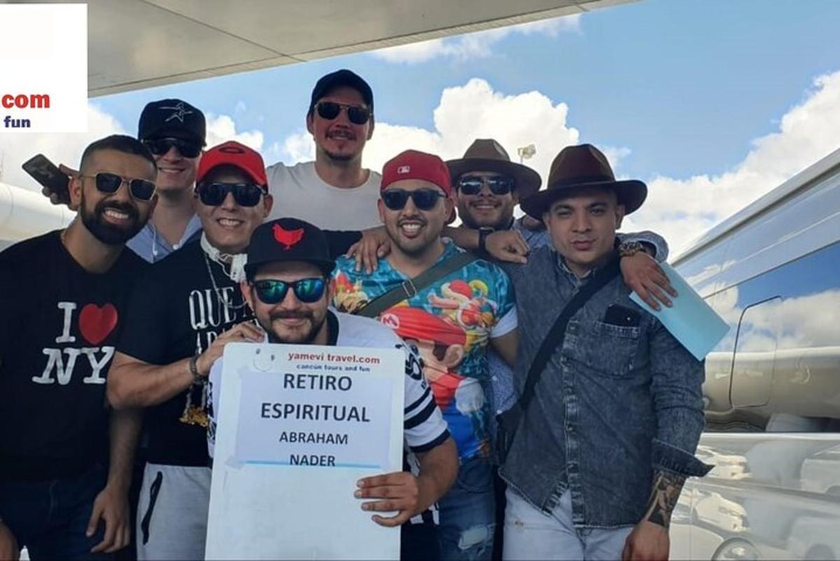 skupina mužů pózujících pro fotografii s cedulí