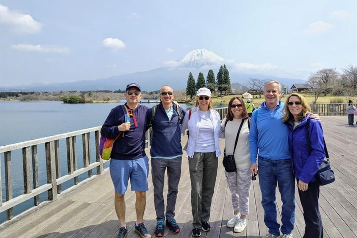 a group of people standing on a pier with a mountain in the background