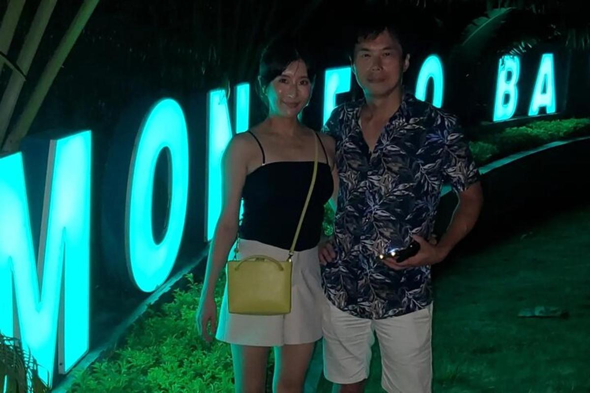 isang lalaki at isang babae na nakatayo sa harap ng isang karatula