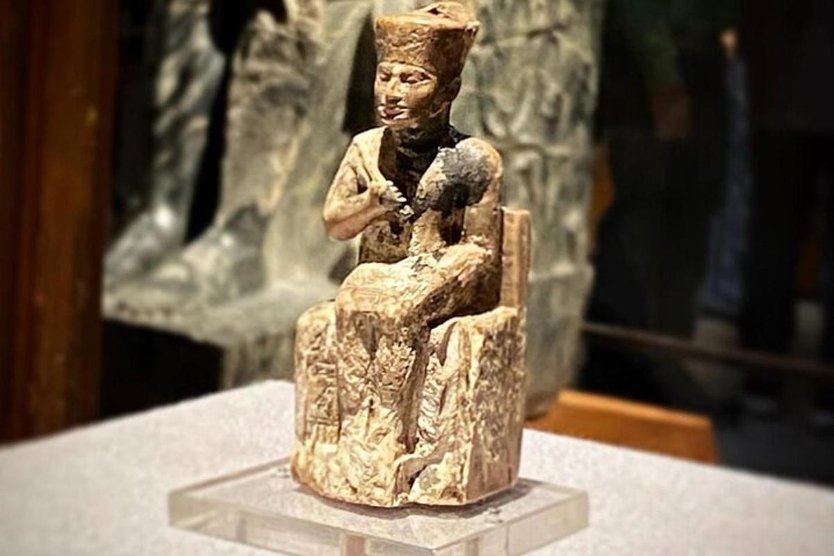 uma estátua de uma pessoa sentada em uma mesa