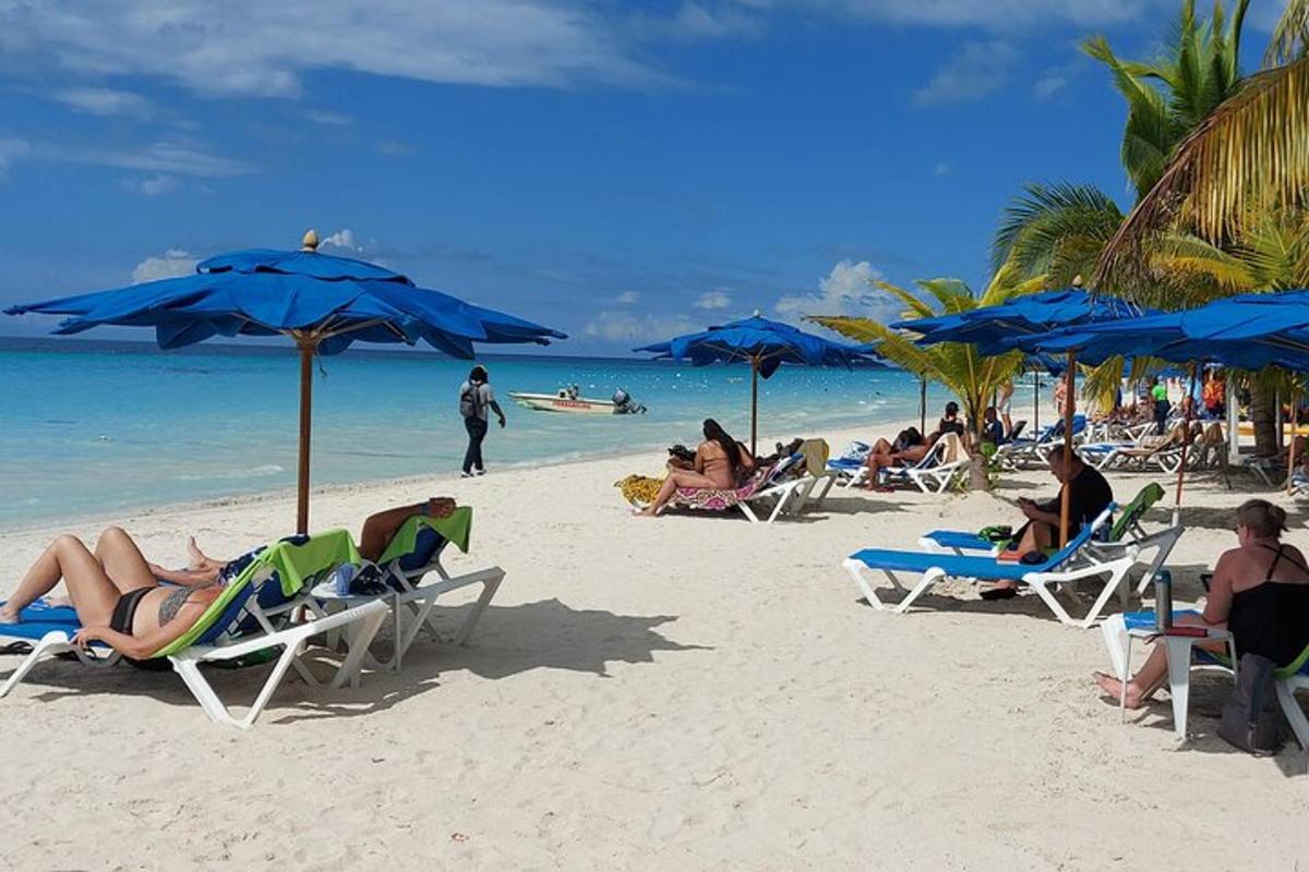 en gruppe mennesker som sitter på en strand med blå parasoller
