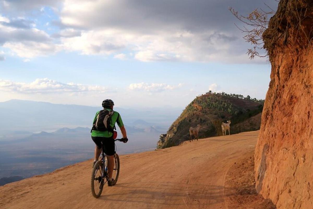 um homem andando de bicicleta em uma estrada de terra
