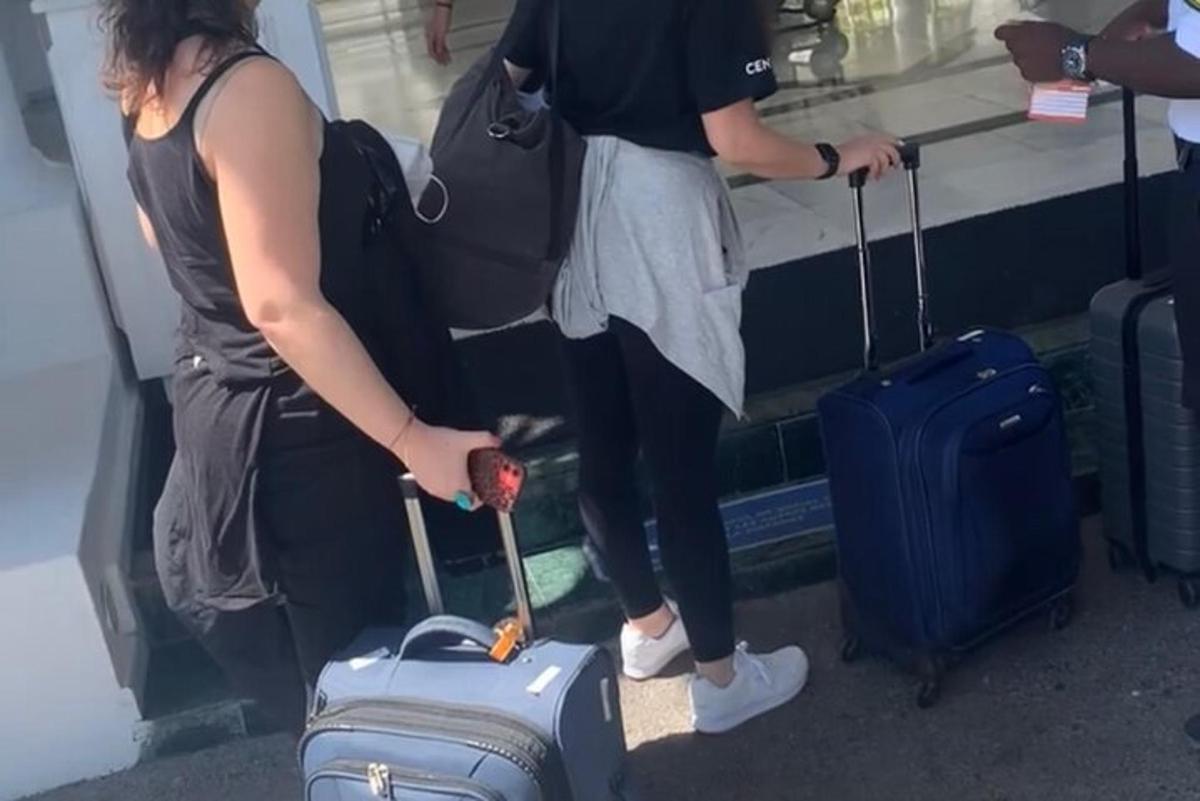 two people are standing with their luggage