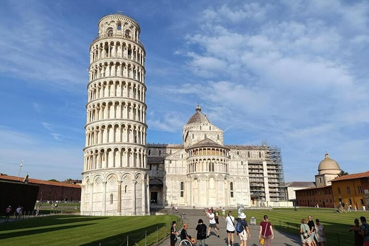 um grupo de pessoas caminhando em frente à torre inclinada