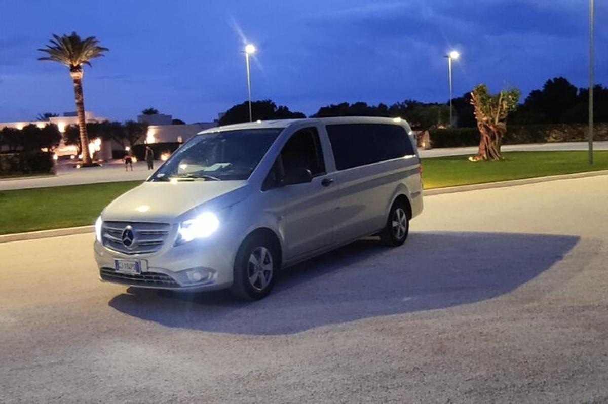 een zilveren busje geparkeerd op een parkeerplaats 's nachts