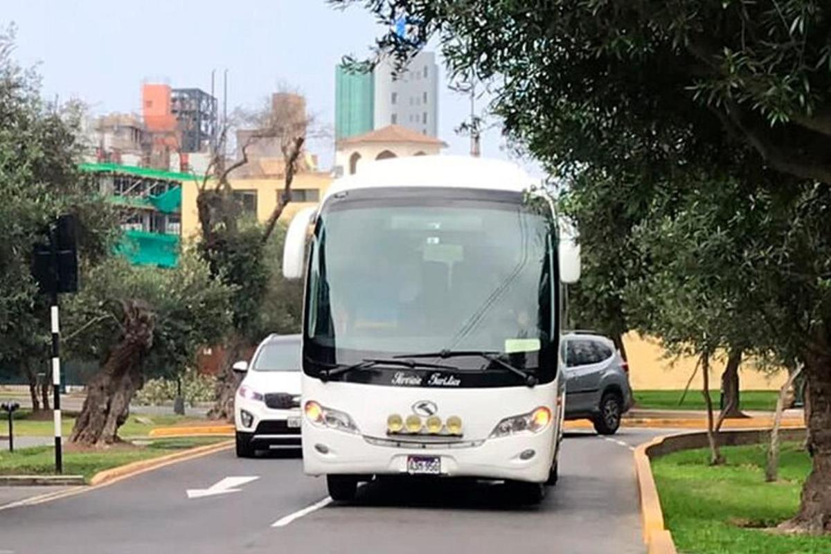 valge buss sõidab mööda tänavat, kus on palju autosid
