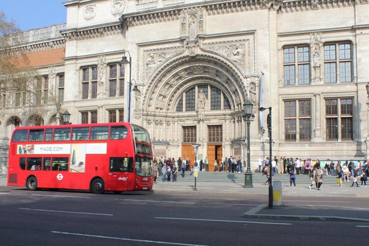 a red double decker bus driving in front of a building