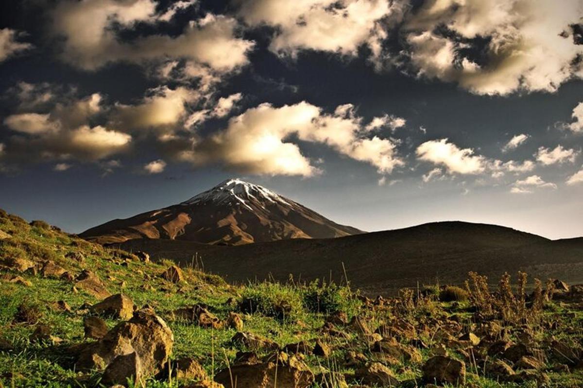 una montagna in mezzo a un campo con nuvole