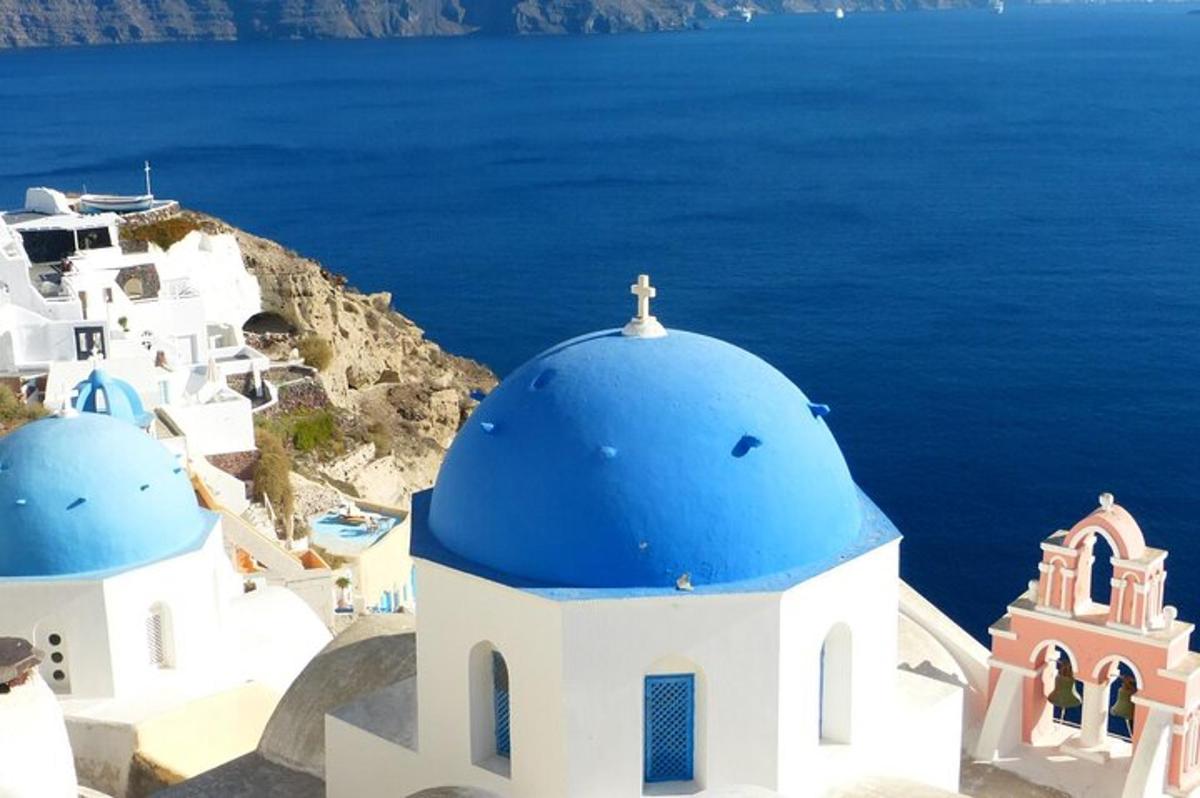 un gruppo di chiese bianche con cupole blu e l'oceano