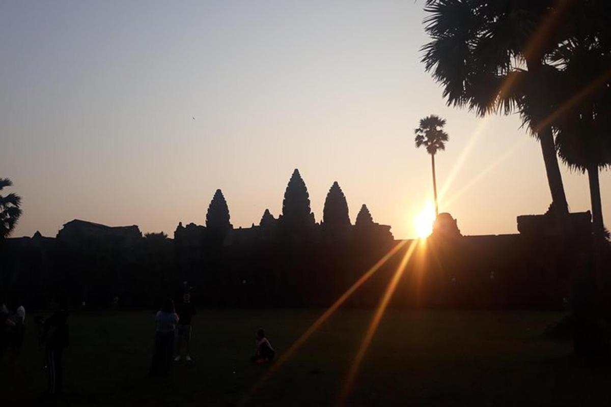 Una puesta de sol sobre las ruinas de un templo con palmeras.