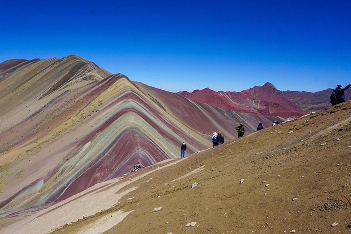Un grupo de personas subiendo una colina con montañas de colores.
