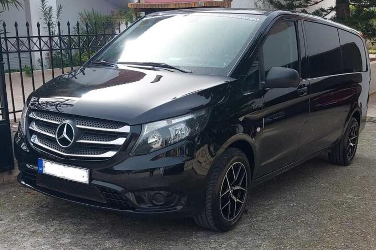 Černá dodávka Mercedes Benz zaparkovaná vedle plotu