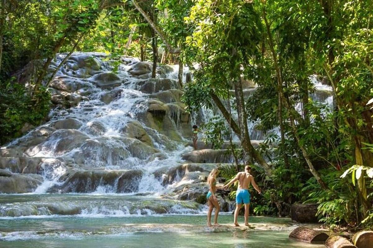 due persone in piedi nell'acqua di fronte a una cascata