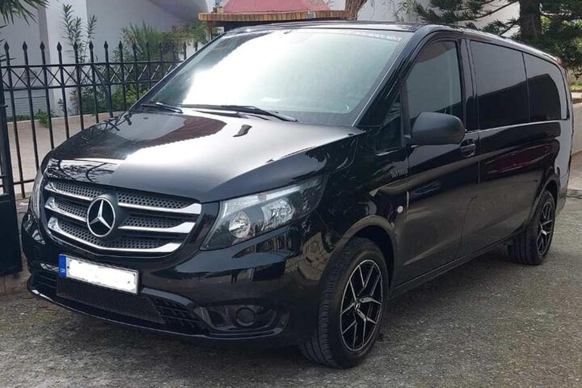 чорний фургон Mercedes Benz, припаркований біля паркану
